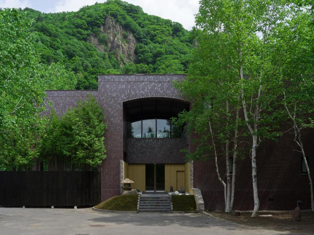 Suigan في Jozankei: مبنى من الطوب مع نافذة كبيرة وأشجار