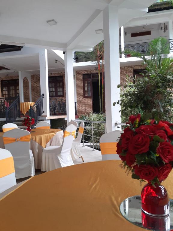 een tafel met een vaas met rode rozen erop bij Hotel Kintop in Udugama