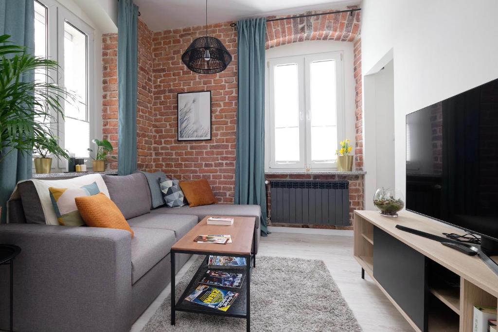 uma sala de estar com um sofá e uma parede de tijolos em Mikroklimatyczny apartament dla 4 osób em Szklarska Poręba