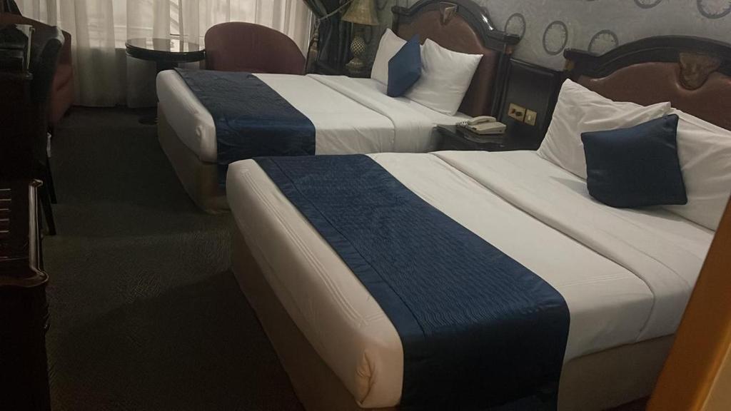 a hotel room with two beds with blue and white sheets at SUN & SANDS HOTEL LLC in Dubai