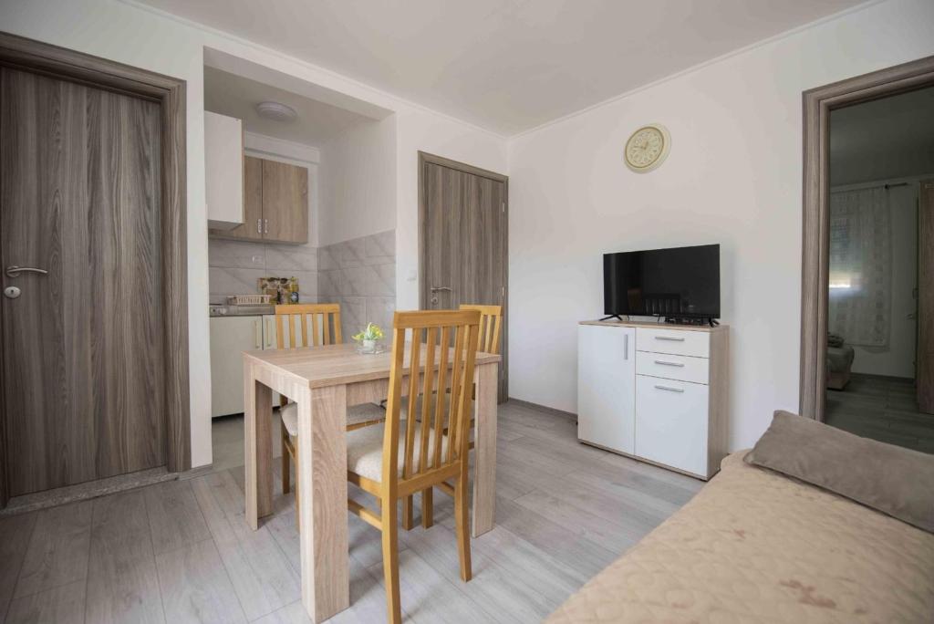 a living room with a wooden table and a kitchen at Apartment Miske in Ivanica