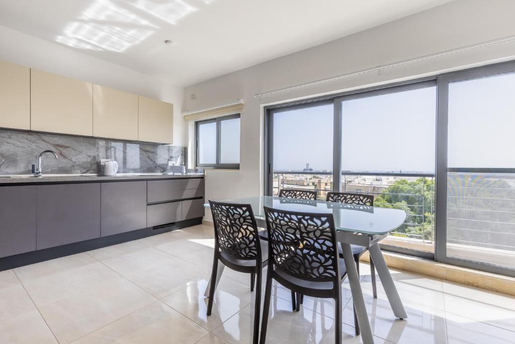 uma cozinha com mesa, cadeiras e janelas em New top floor apartment enjoy opening views em San Ġwann