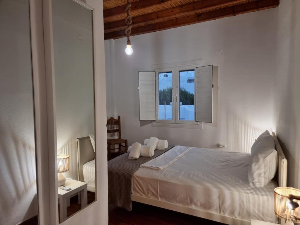 a white bedroom with a bed and a window at Anthoula Home Paros in Naousa