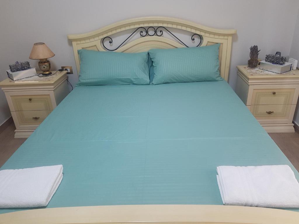 um quarto com uma cama azul com duas mesas de cabeceira em Tirana Central Apartment em Tirana