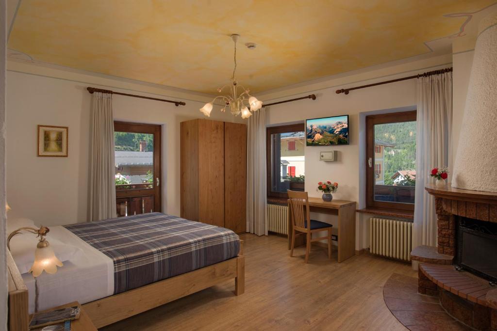 Hotel Centrale في أليغي: غرفة نوم مع سرير ومكتب ومدفأة