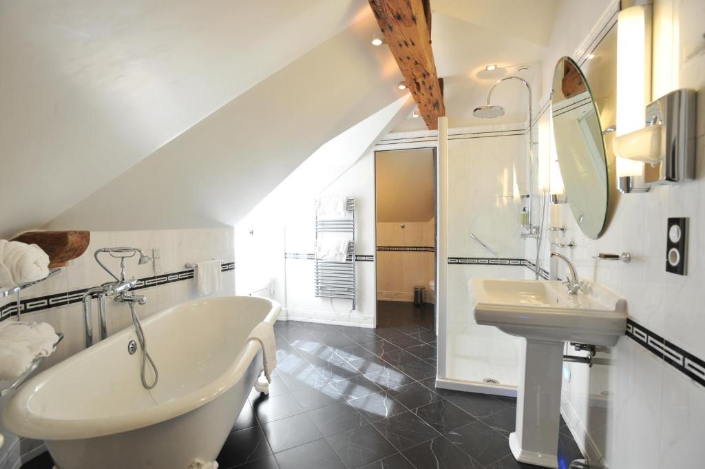 a bathroom with a sink and a tub and a mirror at Dormy House in Étretat