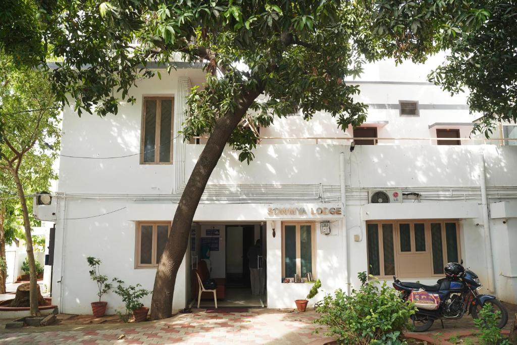 a white building with a motorcycle parked in front of it at SOWMYA LODGE in Tiruchchirāppalli