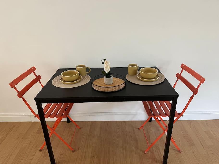 een zwarte tafel met twee stoelen, kopjes en borden bij 3 bedrooms flat Crystal Palace in Londen