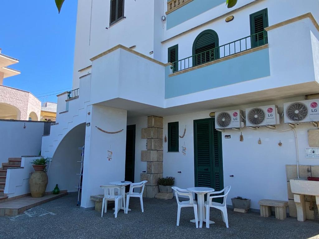 a white building with tables and chairs in front of it at Lecce Rooms in Castro di Lecce