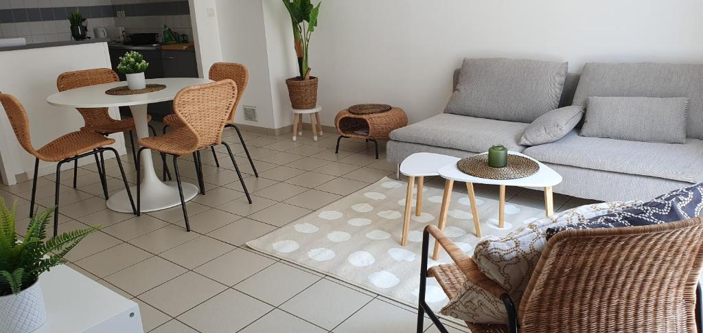 sala de estar con sofá, mesas y sillas en L'Appart' - ADRIAE Home, en LʼAiguillon-sur-Mer