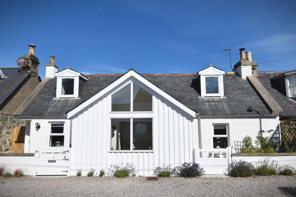 een wit huis met een zwart dak bij Dram Cottage, Findhorn Bay in Forres
