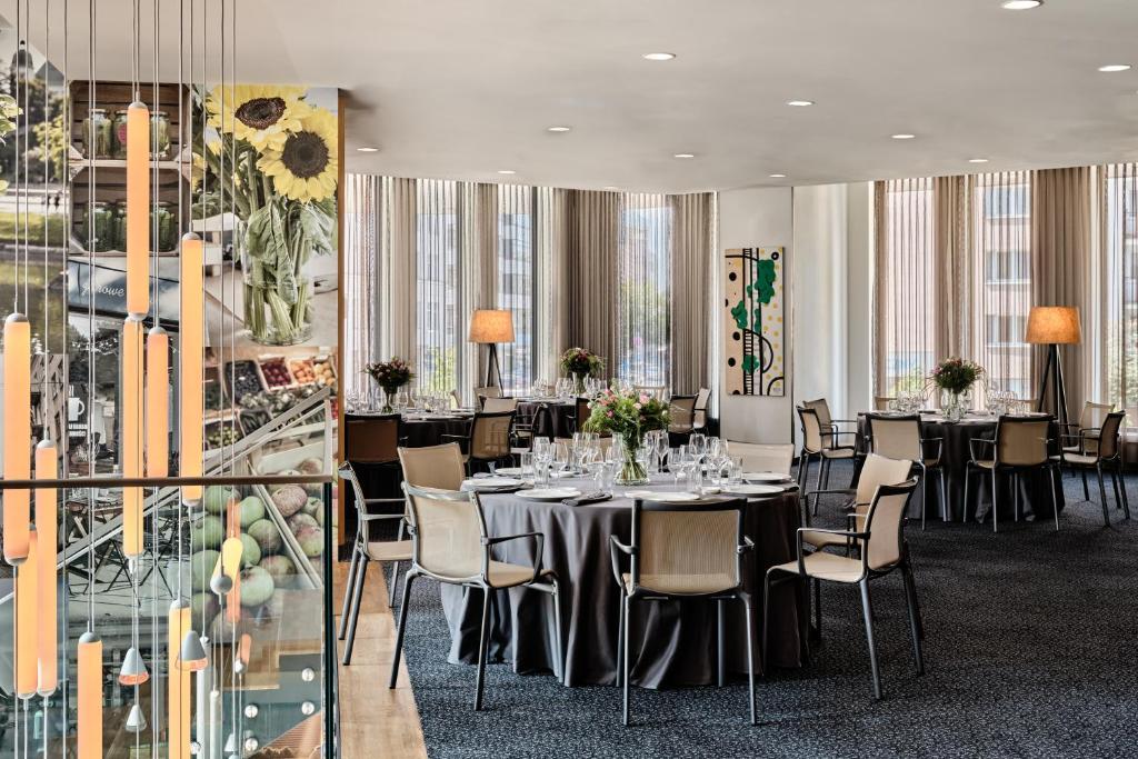ein Esszimmer mit Tischen und Stühlen und Fenstern in der Unterkunft Holiday Inn - Warsaw City Centre by IHG in Warschau
