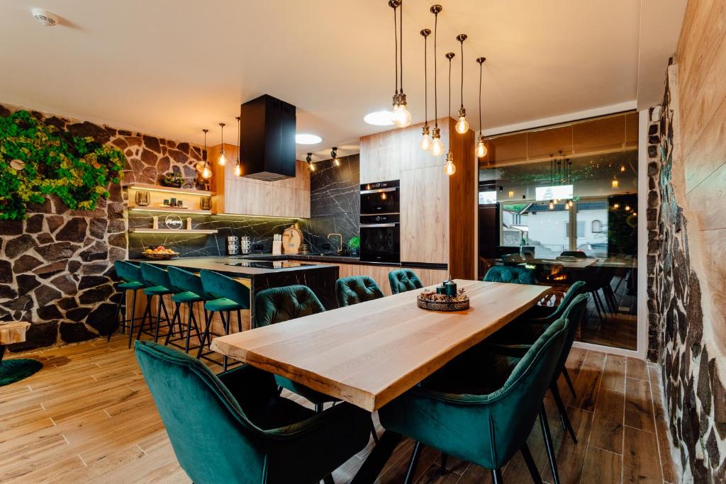 a dining room with a wooden table and green chairs at PARADiSE Wellness Residence in Terchová