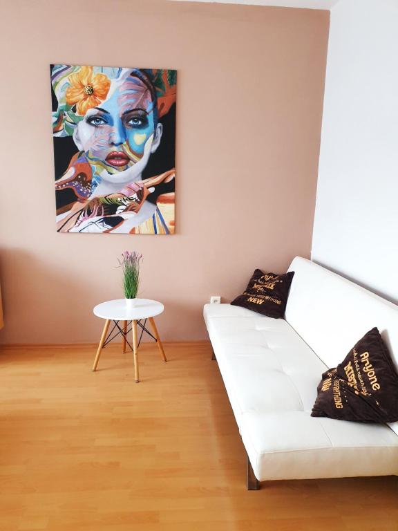 a living room with a white couch and a painting at Apartmán Terminál, self check-in 24 h in Banská Bystrica
