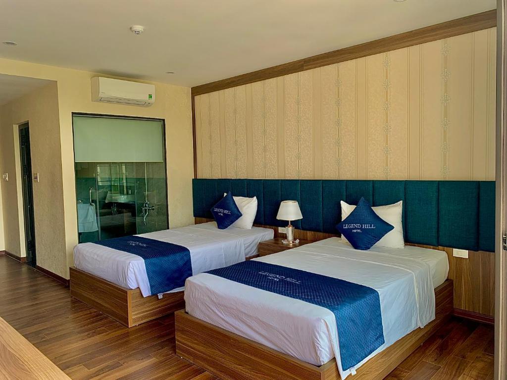 a bedroom with two beds with blue and white sheets at Thái Nguyên Legend Hill in Thái Nguyên