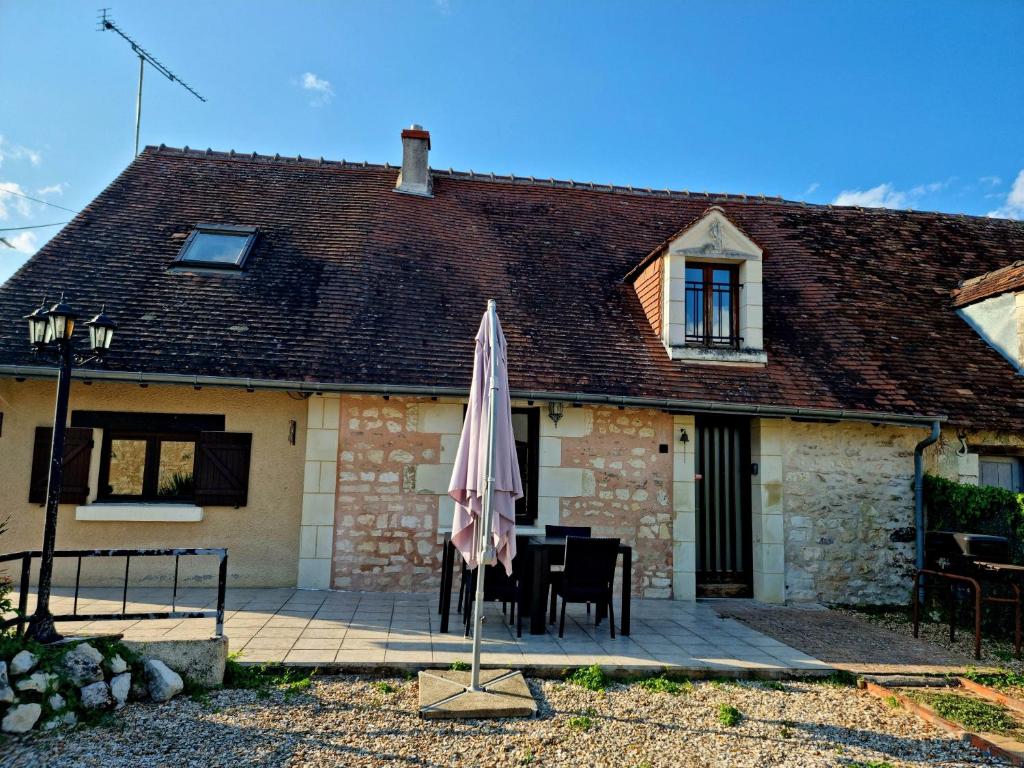 a house with a table and an umbrella in front of it at Maison de campagne à 15 km du ZooParc de Beauval in Luçay-le-Mâle