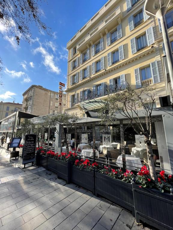 a hotel with tables and chairs in front of a building at Hôtel & Appartements Monsigny in Nice