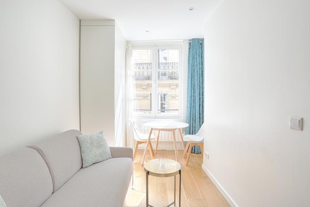 uma sala de estar com um sofá, uma mesa e uma janela em Ciseaux 4F - Studio in Saint Germain des Prés em Paris