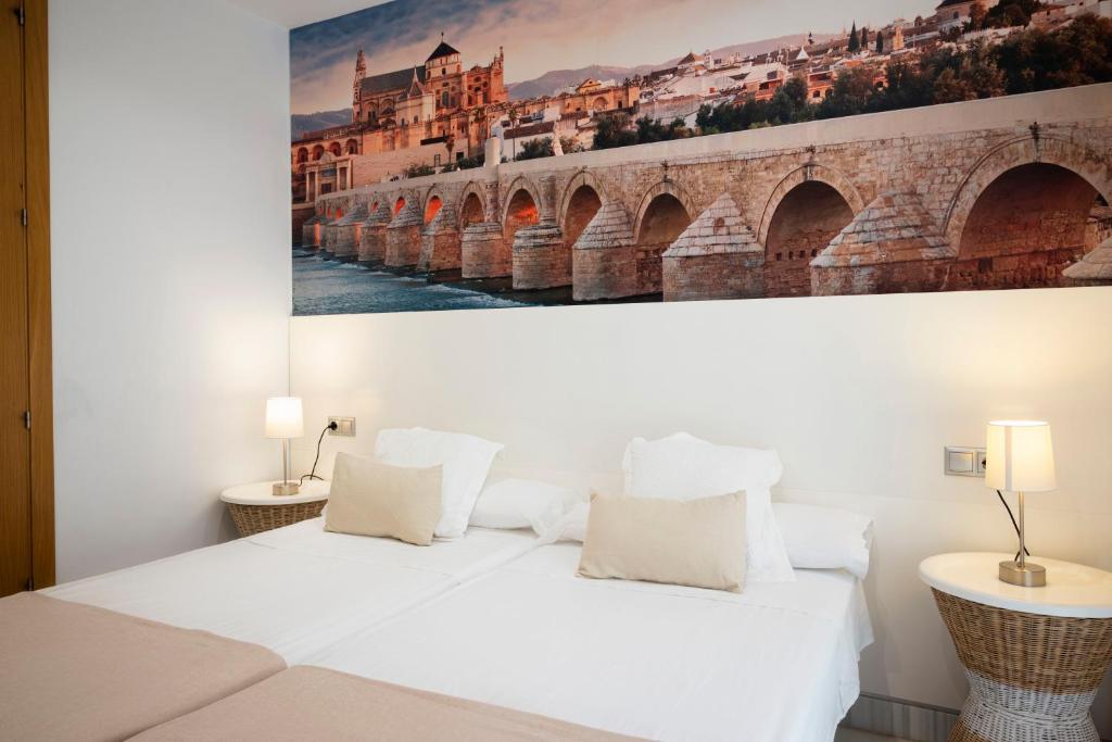 1 dormitorio con 1 cama blanca y una pintura en la pared en Monteras Córdoba Centro en Córdoba