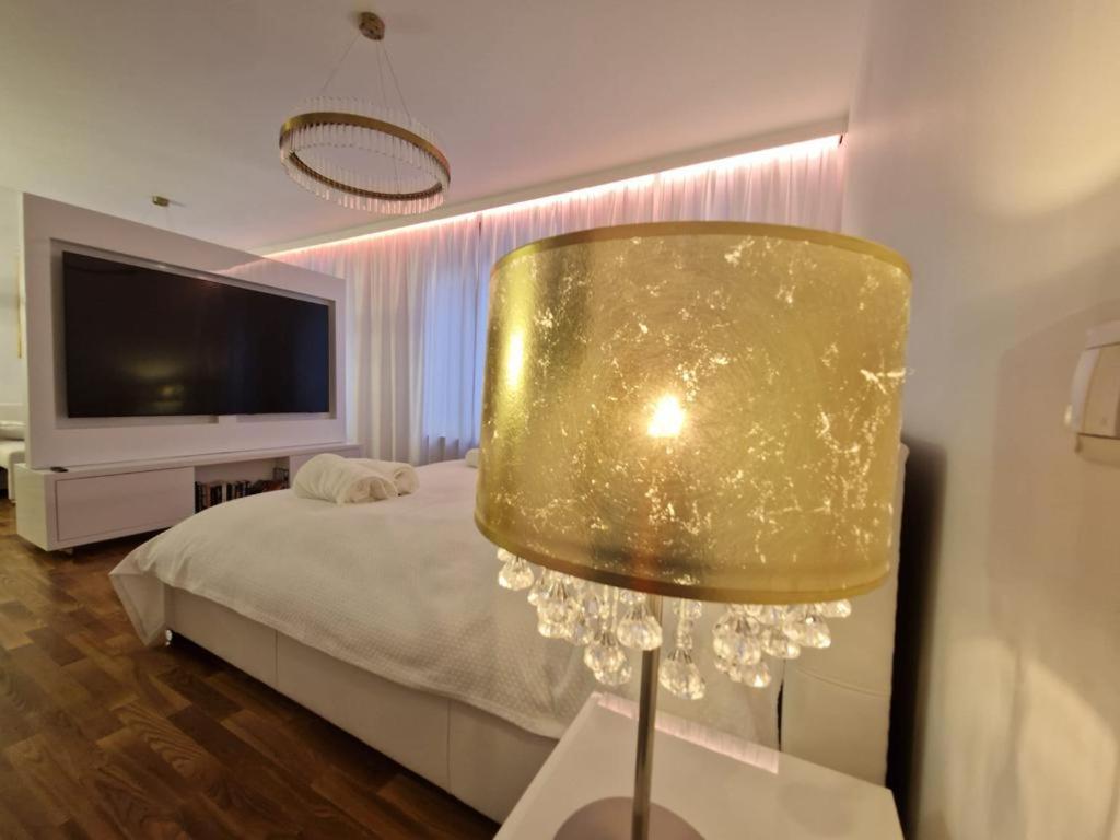 a bedroom with a bed and a gold lamp at Luxury Princessa Apartment & garage & cable tv channels in Warsaw