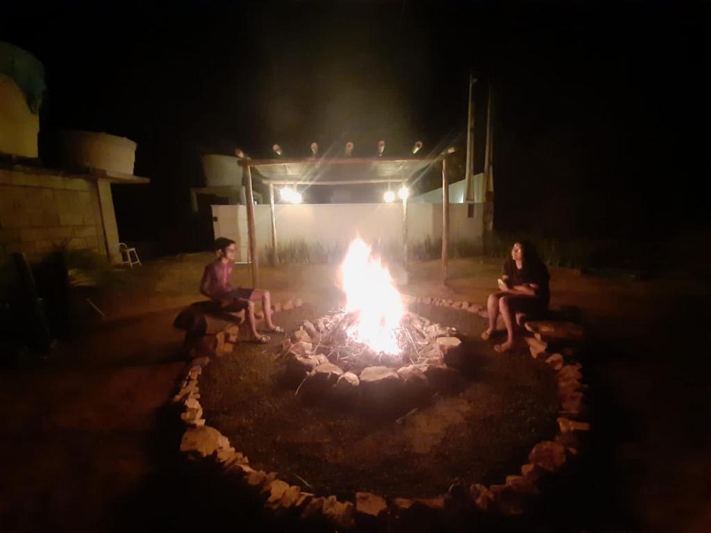 dos personas sentadas alrededor de una hoguera por la noche en tranquilidade en Serra Negra