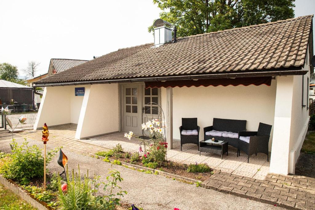 een klein wit huis met zwarte stoelen en een veranda bij Ferienhaus Blick Falkenstein in Lindberg