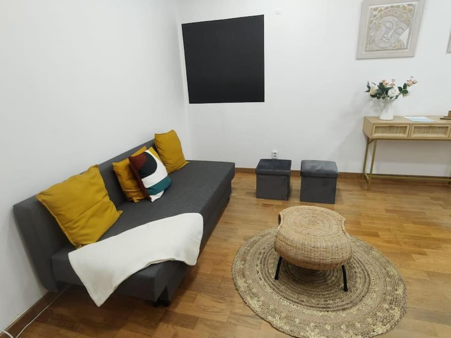uma sala de estar com um sofá preto com almofadas amarelas em Sweet Little Orange em Lisboa
