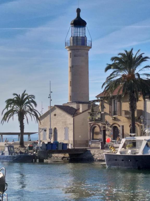 un phare sur l'eau à côté d'un bâtiment dans l'établissement Authentique maison de pêcheur, au Grau-du-Roi