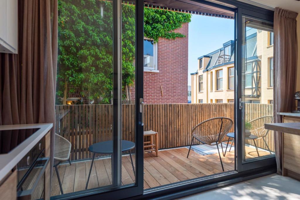 een balkon met glazen schuifdeuren en een tafel en stoelen bij The Modern Burrow in Zandvoort