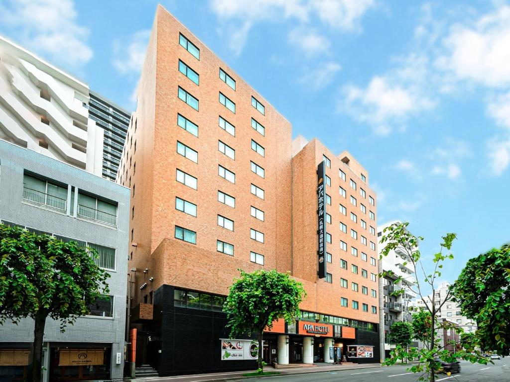 a tall red brick building on a city street at APA Hotel Sapporo Odori Ekimae Minami in Sapporo