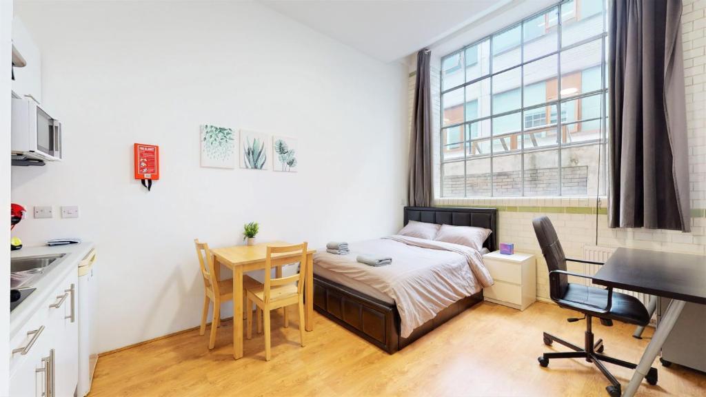 Habitación pequeña con cama, escritorio y mesa. en Amazing Studio Apartment en Londres