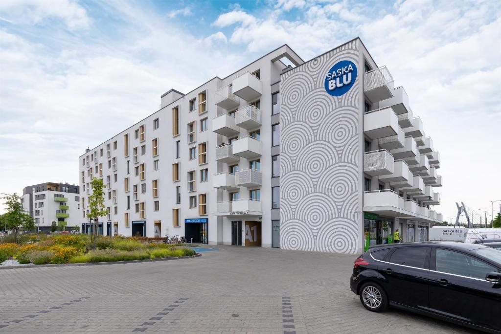 un edificio con un coche aparcado delante de él en Saska Blu Studio Apartments Podgórze by Renters en Cracovia