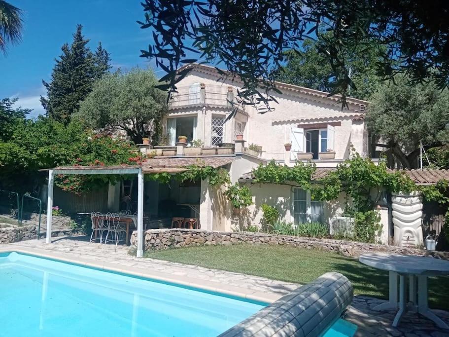 eine Villa mit einem Pool vor einem Haus in der Unterkunft Belle villa de charme avec piscine in Tourrettes