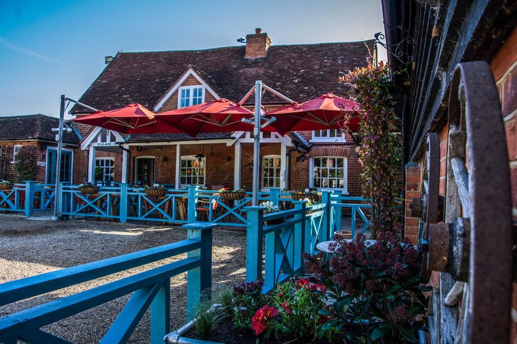 a house with a blue fence and red umbrellas at The Winning Post in Windsor