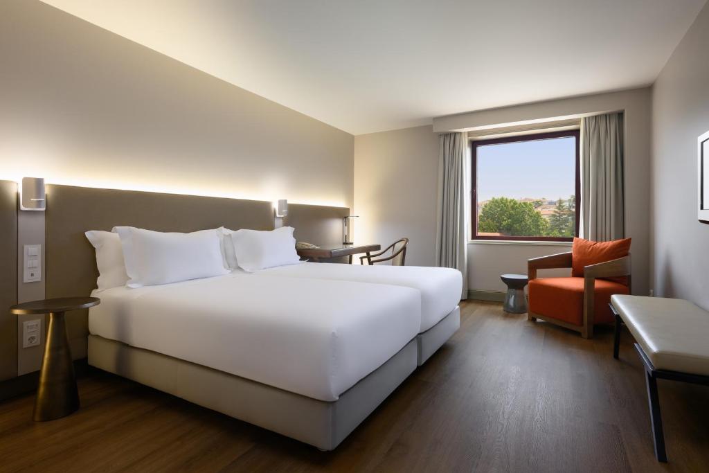 a hotel room with a bed and a chair at Hotel Coimbra Aeminium, Affiliated by Meliá in Coimbra