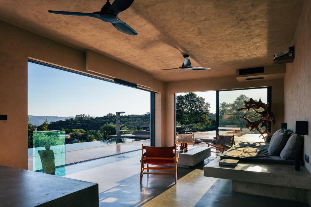 a living room with a ceiling fan and large glass windows at Inspiration House in Souda