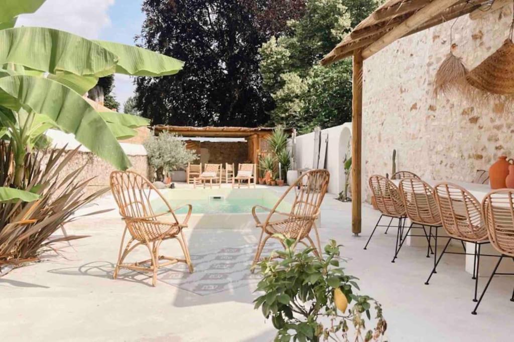 a patio with chairs and a table and a pool at Maison Hortense 4 étoiles piscine chauffée et sauna in Buxeuil
