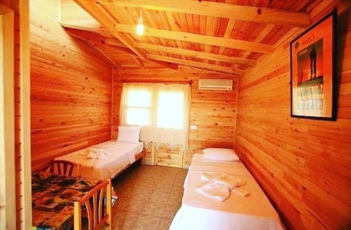a bedroom with two beds in a wooden cabin at HALİSE APART in Emecik
