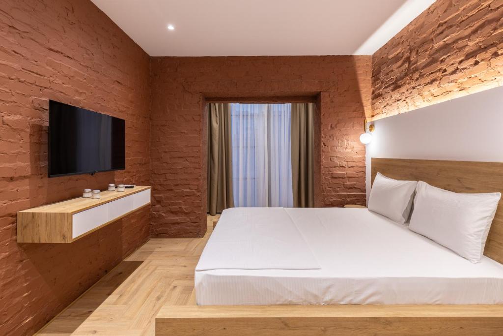 - une chambre avec un lit blanc et une télévision sur un mur en briques dans l'établissement Vatër Apartments, à Tirana