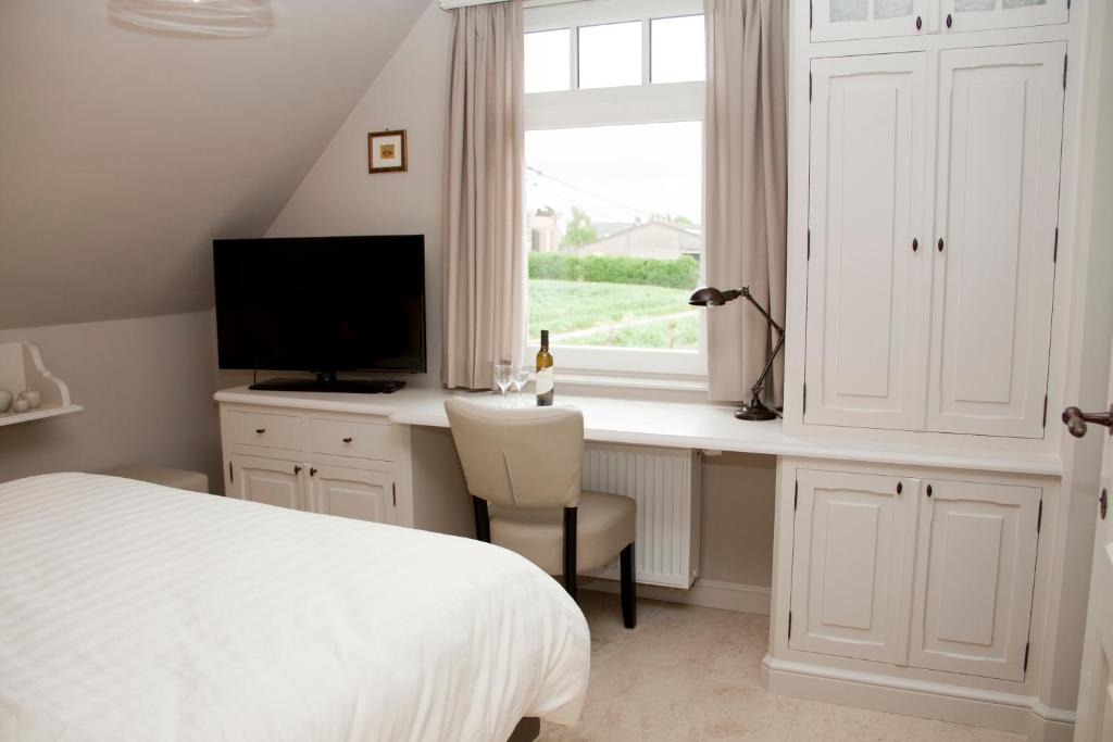 a bedroom with a bed and a desk and a window at B&amp;B - Ter Douve in Dranouter