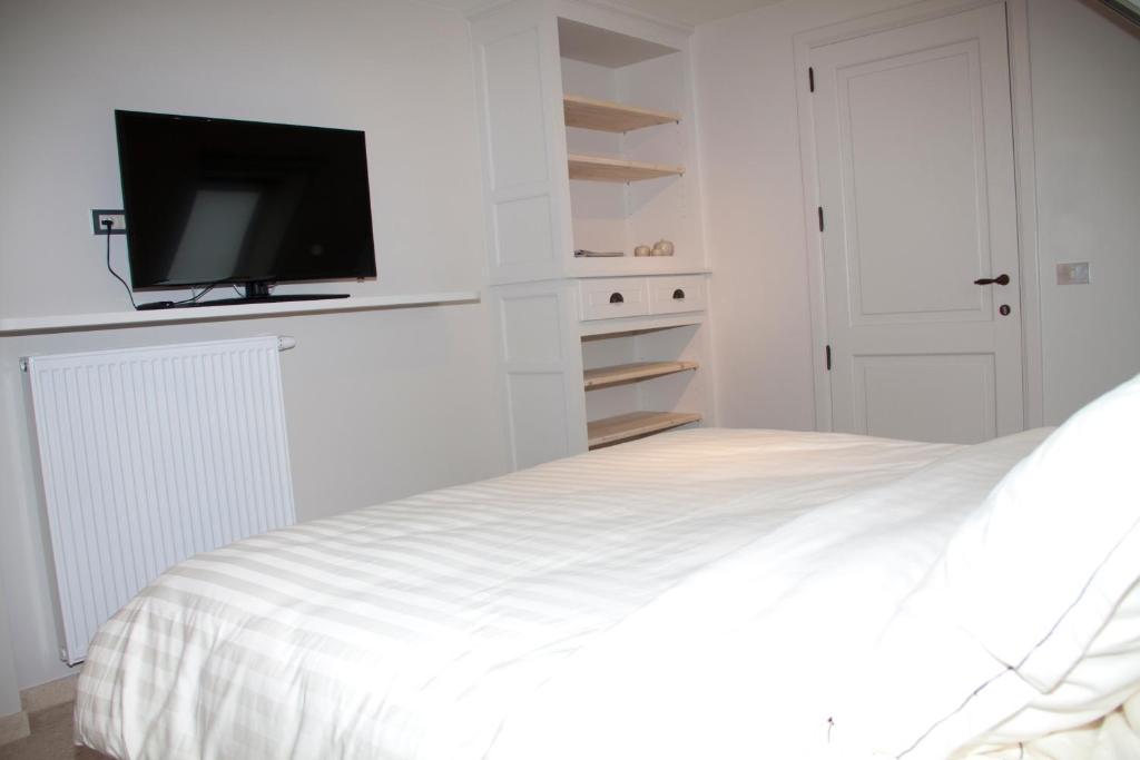 a white bedroom with a bed with a flat screen tv at B&amp;B - Ter Douve in Dranouter