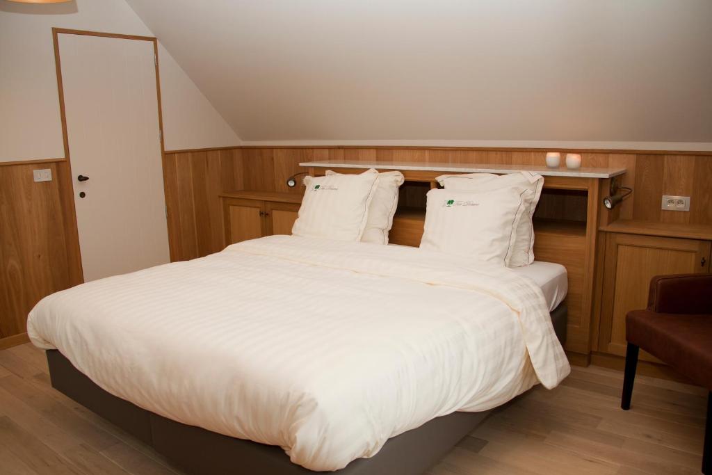 a bedroom with a large bed with white sheets at B&amp;B - Ter Douve in Dranouter