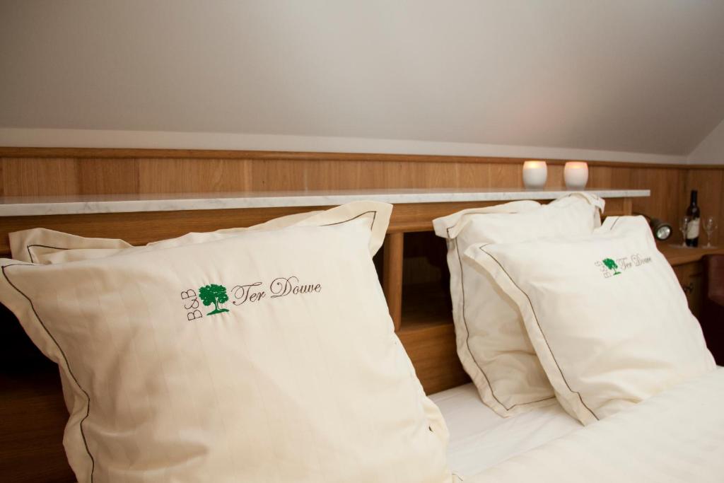 a bed with two white pillows on top of it at B&amp;B - Ter Douve in Dranouter