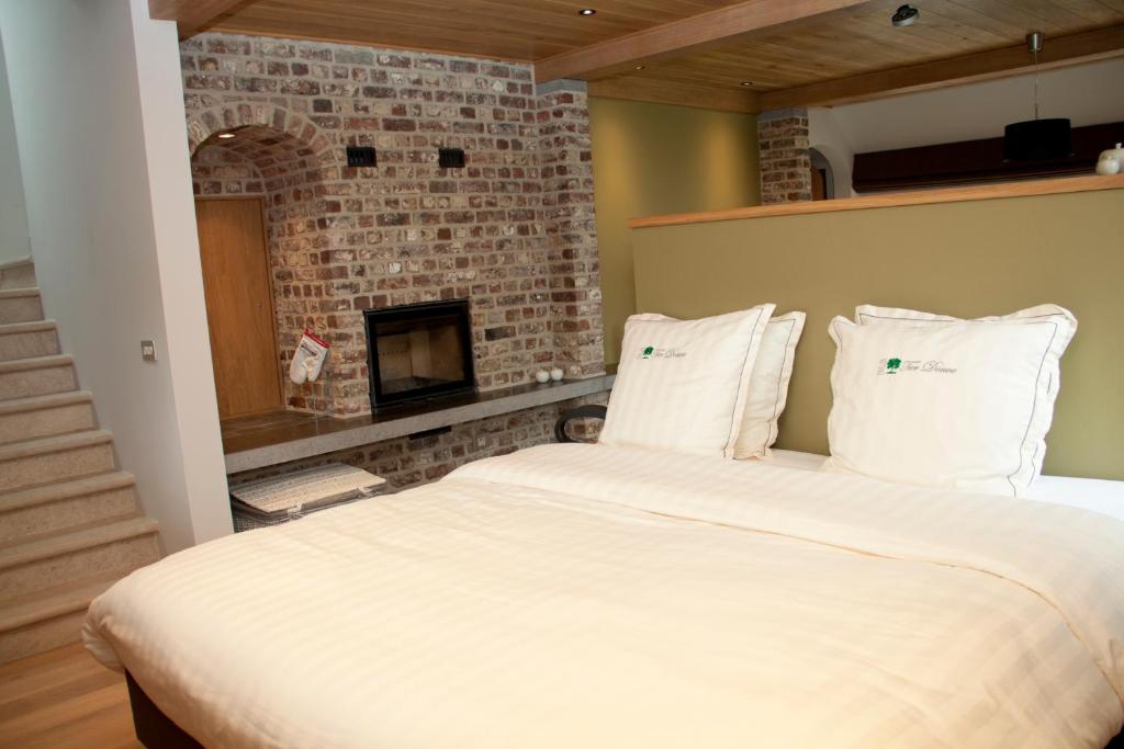 a bedroom with a large bed with a brick fireplace at B&amp;B - Ter Douve in Dranouter