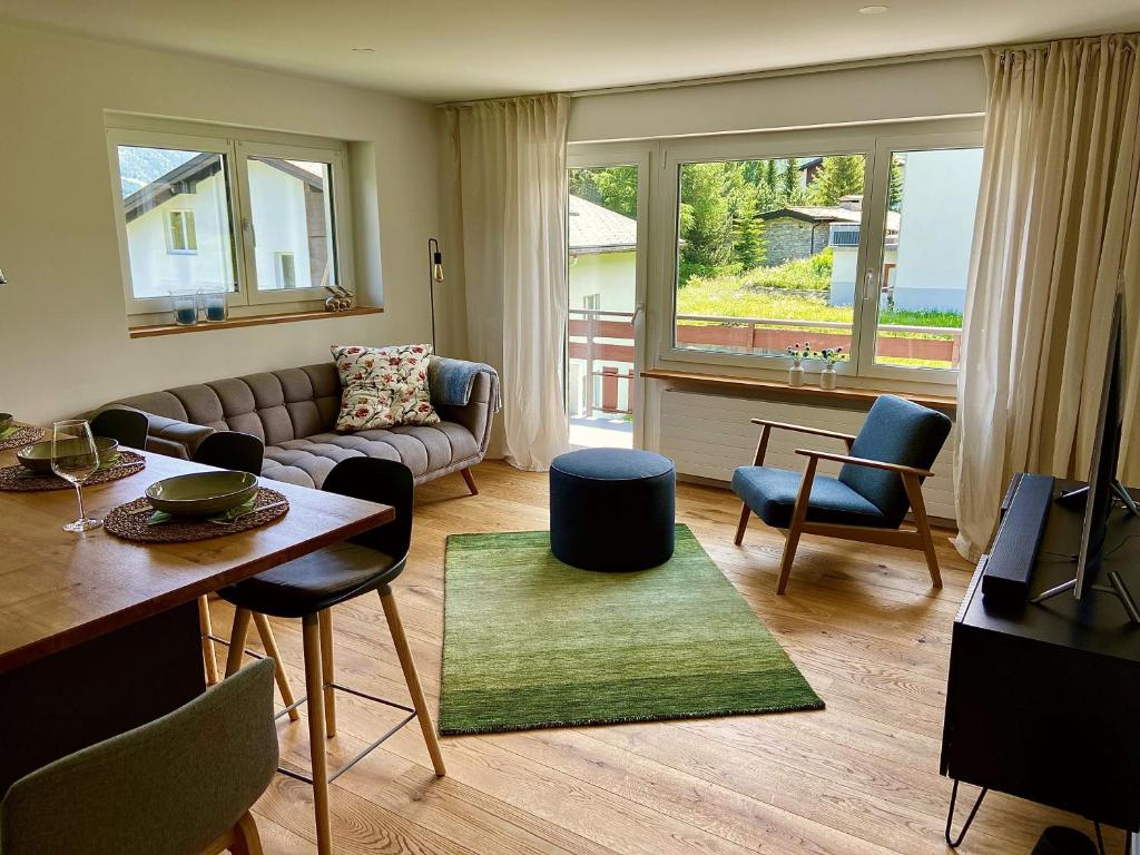 uma sala de estar com um sofá, uma mesa e cadeiras em Appartment Alpenrose em Saas-Fee