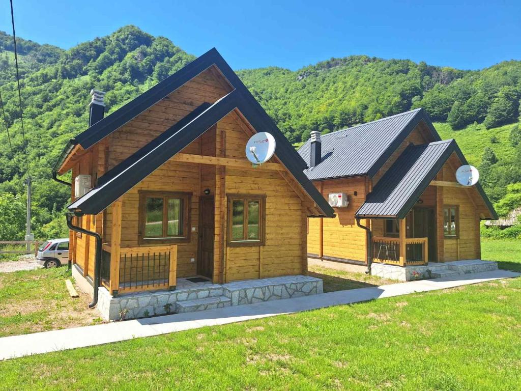 a wooden house with a mountain in the background at Riverland Cottage 1 in Kolašin