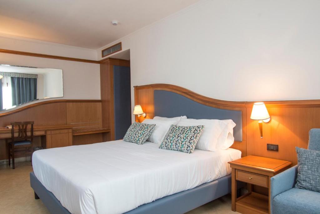 a bedroom with a white bed and a blue chair at Hotel Centrale in Sabaudia