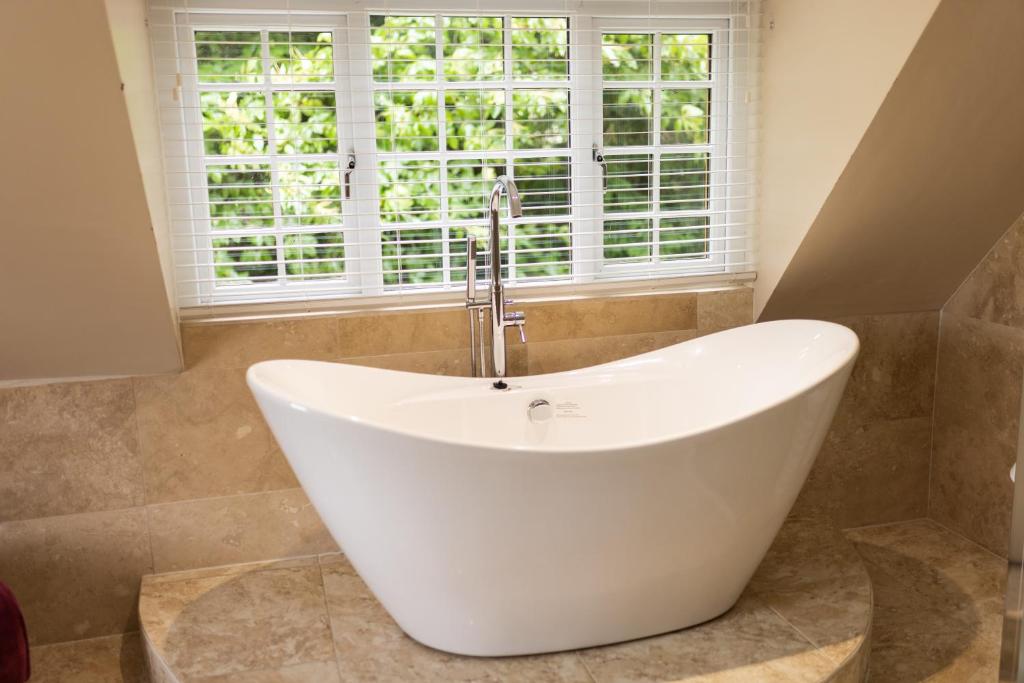 La salle de bains est pourvue d'une baignoire et d'une fenêtre. dans l'établissement Romantic Cottage, à Plymouth