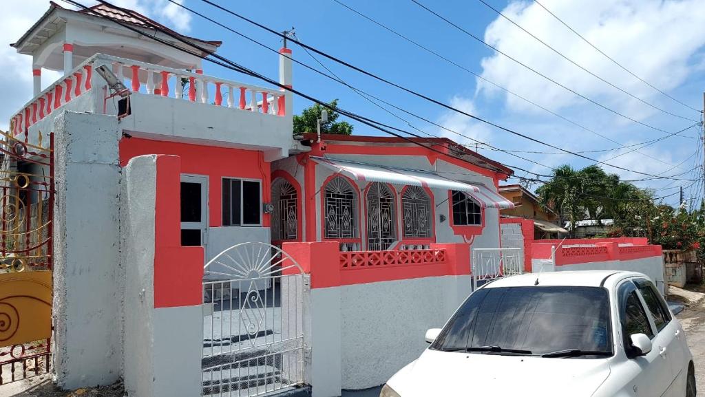 a white car parked in front of a red building at Beautiful 1-Bedroom in St Thomas Jamaica in Belfast