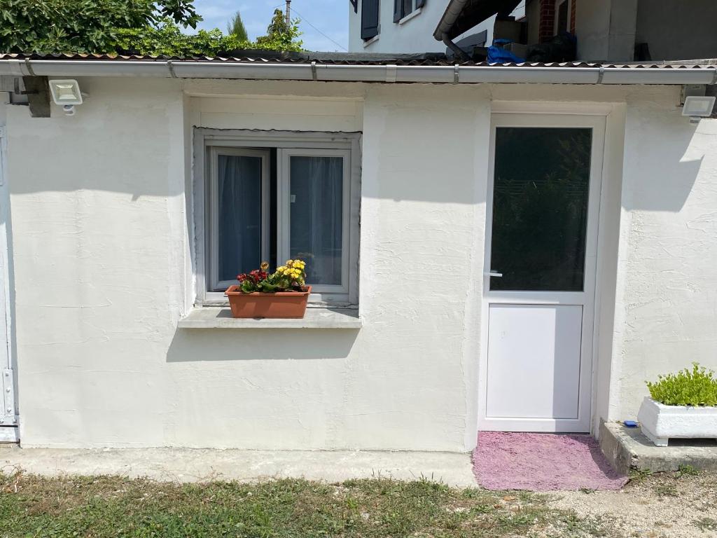 uma casa branca com uma janela com um vaso de flores e uma porta em Loue studio meublée les Abrets en Dauphiné 38 em Les Abrets